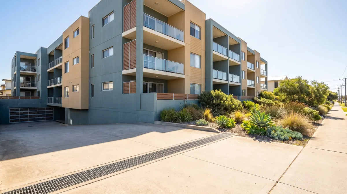 An apartment building with a shared drainage grate set into its paved forecourt